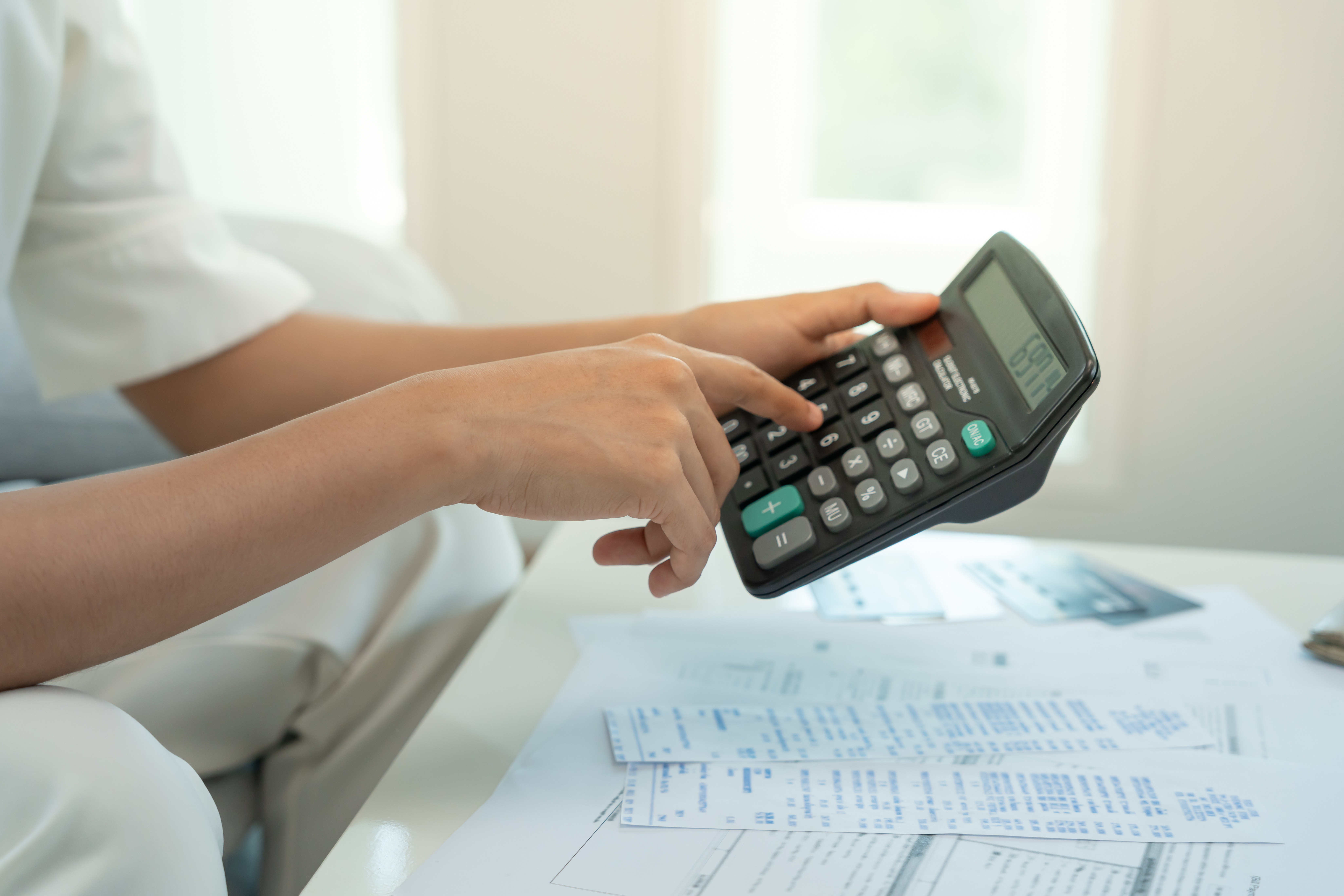 A homeowner tallying rebate savings with a calculator over paperwork