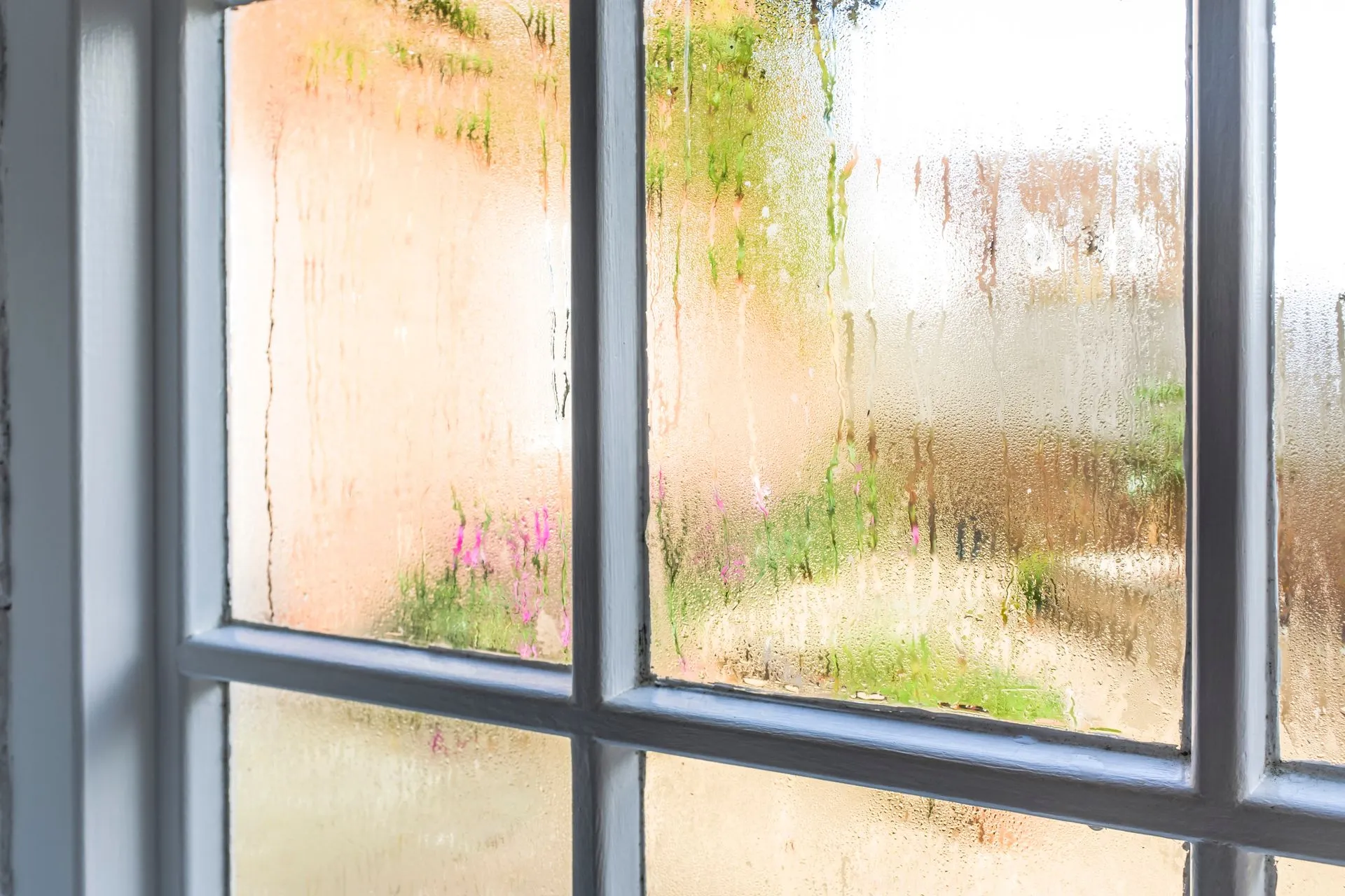 Condensation covering the inside of a home window on a humid summer day